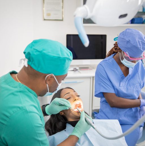 An African dentist checks the oral health of his patient while his assistant prepares the work tools.